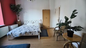 Une chambre à coucher avec un lit, une armoire en bois, une plante en pot, une chaise et une table.