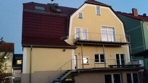 Un immeuble de deux étages doté d’un balcon et d’un escalier menant à l’étage supérieur.