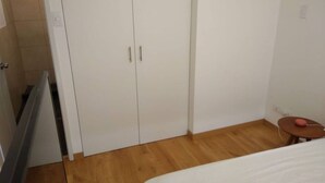 A bedroom with a bed, a small table, and a wardrobe.