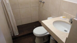 A small bathroom with a white toilet, a beige sink, and a shower curtain.