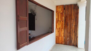 Une pièce avec une porte en bois, un mur blanc et un petit ventilateur.