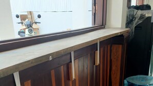 Un coin cuisine avec un comptoir en bois, deux tabourets bleus et une fenêtre donnant sur l’extérieur.