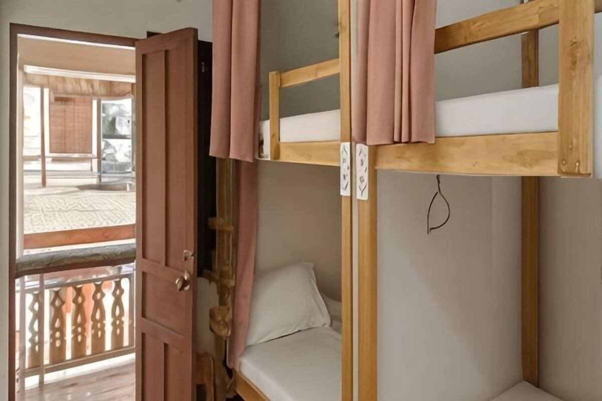 Un lit superposé avec une structure en bois, une porte et une vue sur l’extérieur.