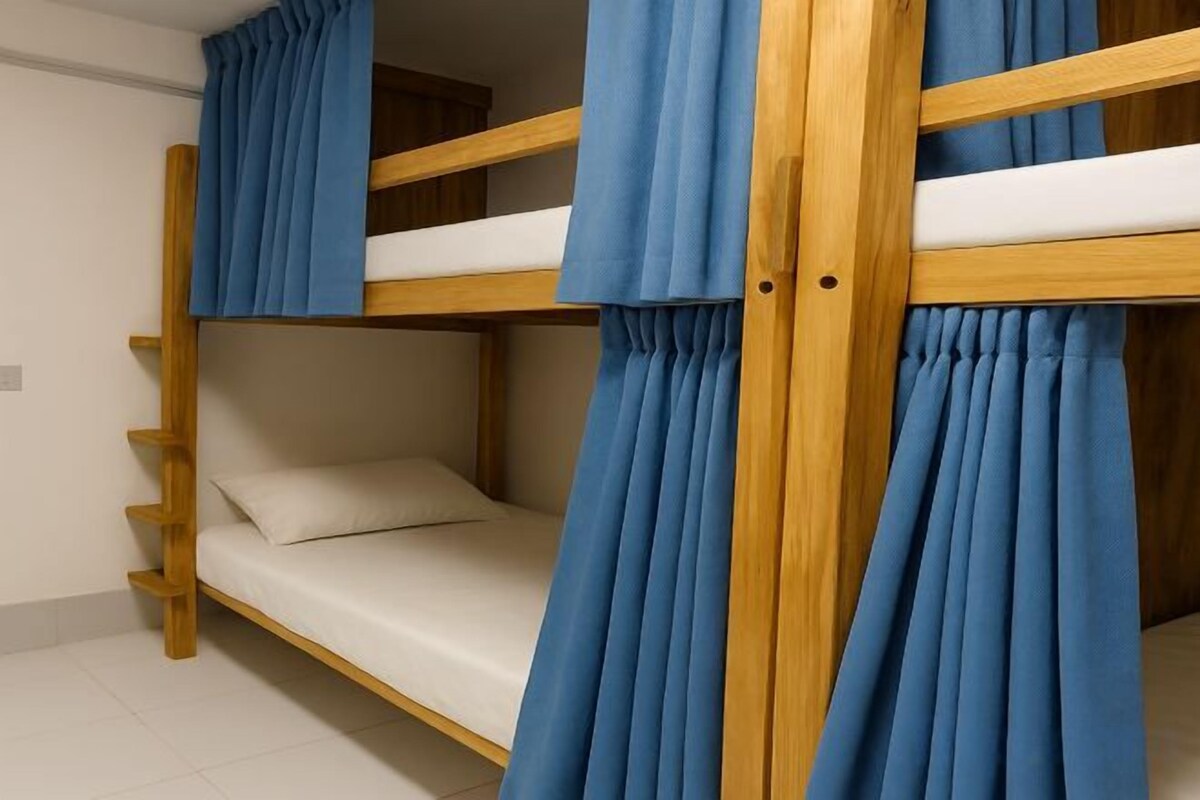 A bunk bed with blue curtains, a wooden frame, and a white mattress.