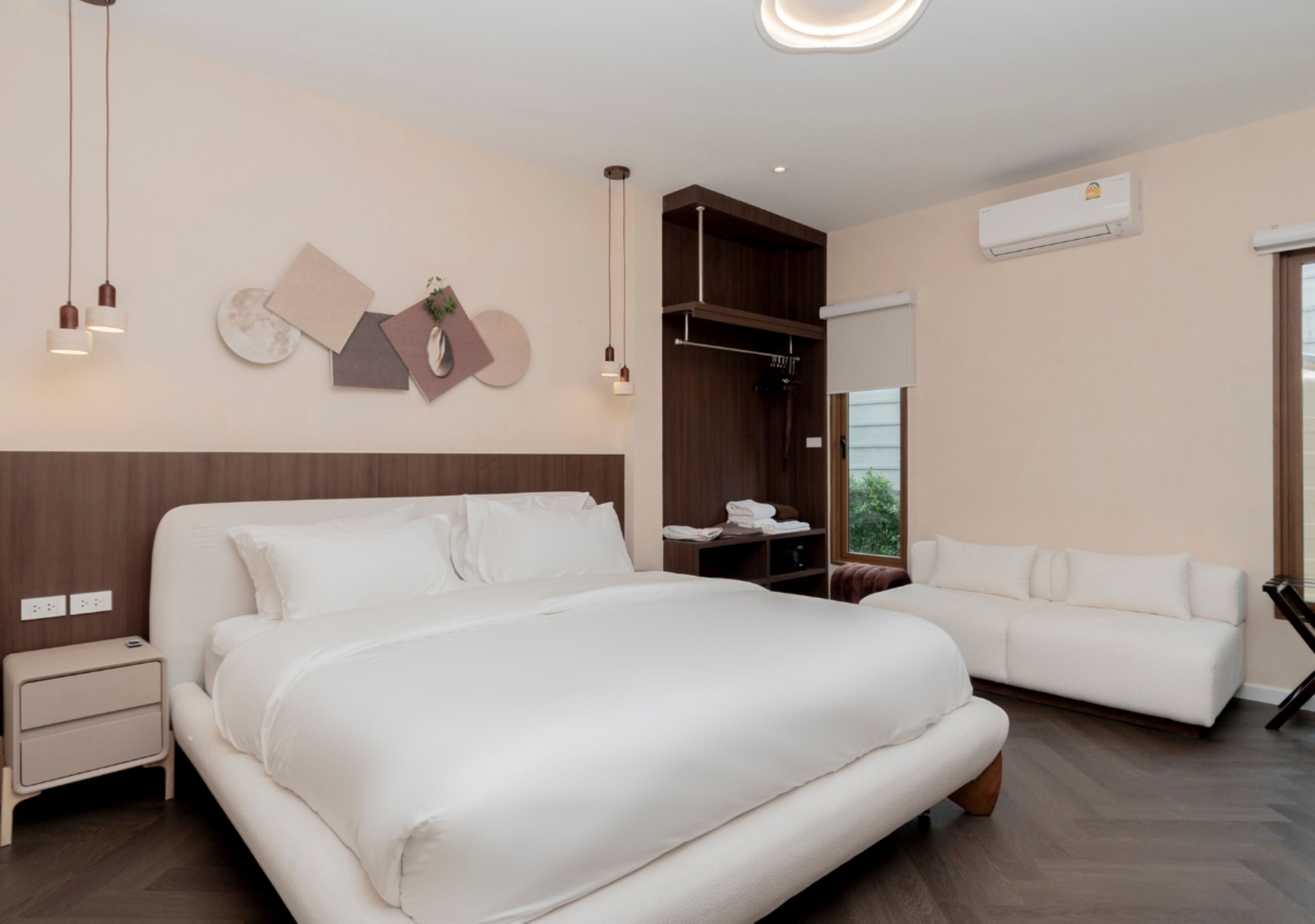 Ein modernes Hotelzimmer mit einem großen Bett, einer Schlafcouch, einem Kleiderschrank und einem Nachttisch.
