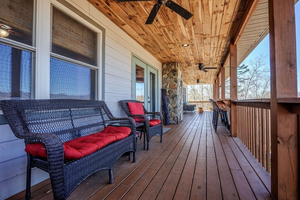 A covered porch with wicker furniture and a stone wall.