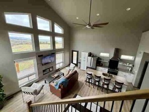 A spacious living area with a large window, a ceiling fan, and a kitchen area with modern appliances.
