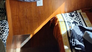 Ein Bett mit karierter Decke und Kissen, einem Baldachin darüber und einem hölzernen Kopfteil.