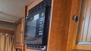 Eine kleine Küchenzeile mit Mikrowelle, Herd und Kaffeemaschine.