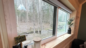 L’intérieur d’un chalet, avec une grande fenêtre donnant sur une forêt, une petite figurine d’ours, une bougie et un panneau sur lequel on peut lire : « Détendez-vous au chalet ».