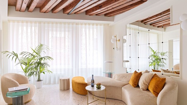 A modern living room with a large sofa, a coffee table, and a potted plant. - Charming Canal View Apartment in Idyllic Location (Venecia)