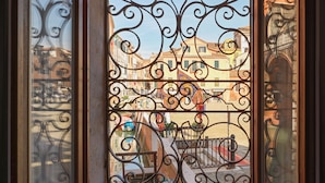 A window with ornate ironwork, offering a view of a canal with boats and buildings. - Charming Canal View Apartment in Idyllic Location (Venecia)