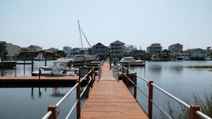 A wooden pier leading to a marina with boats docked, surrounded by residential buildings. - New! Condo with Dock + Pool (Carolina Beach)