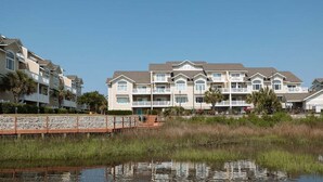 A multi-story hotel with balconies, a waterfront view, and a wooden deck. - New! Condo with Dock + Pool (Carolina Beach)