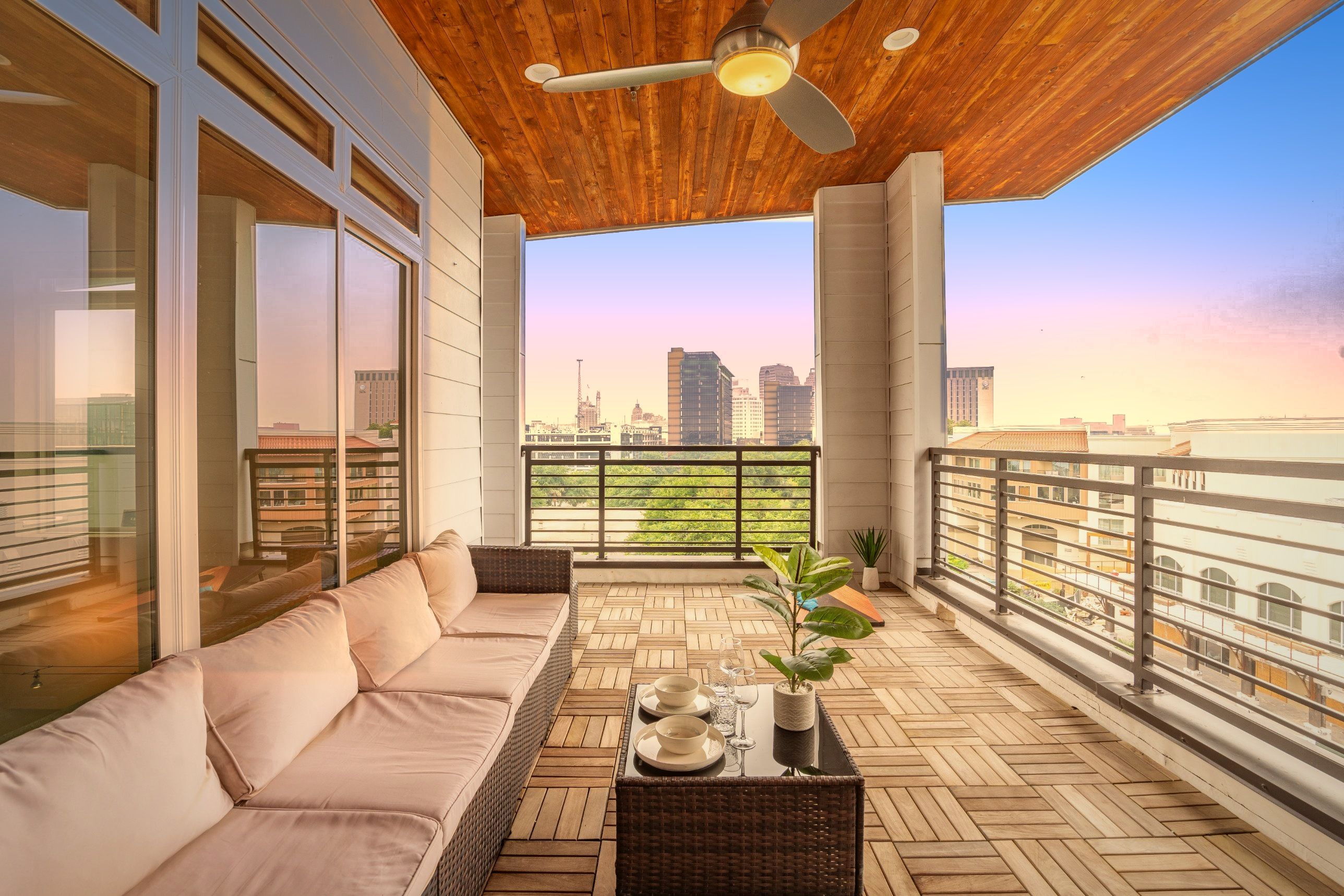 Un balcone con un divano, un tavolino e oggetti decorativi, vista sulla città.