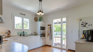 A modern kitchen with white cabinets, a large island, and a view to the outside.