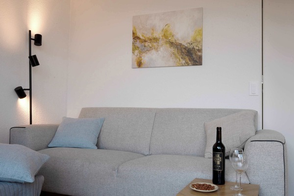 Modern lounge area with cozy touches
Relax with a glass of wine in this bright, inviting space featuring a soft sofa, elegant lighting, and serene artwork.