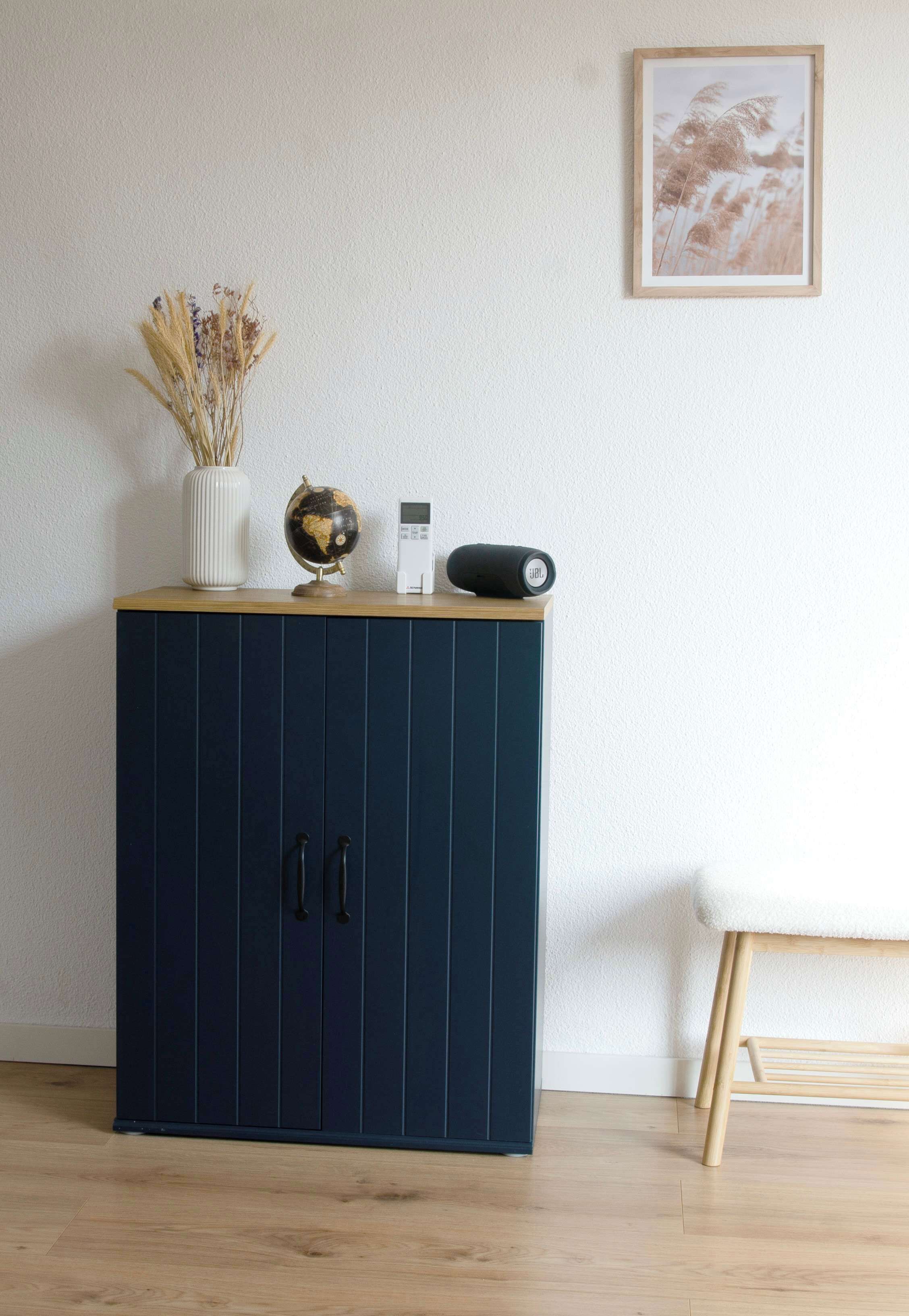Een donkerblauwe kast met twee deuren, een wereldbol, een kleine vaas met gedroogde planten en een ingelijst beeld op de muur.