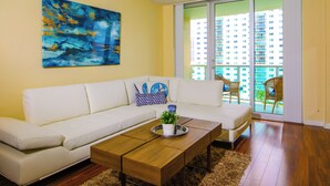 A living room with a white sofa, a coffee table, and a painting on the wall. - Awesome Miami Sunny Isles Ocean Reserve Condo (Sunny Isles Beach)