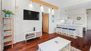 Una sala de estar moderna con un sofá blanco, piso de madera y un televisor montado en la pared.