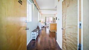 Un pasillo con una puerta de madera identificada con el número '212', que conduce a una zona de cocina con armarios de madera y una encimera.