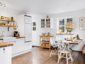 Een koelkast, een oven, een vaatwasser, kookgerei, borden en bestek