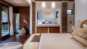 Een slaapkamer met een groot bed, een slaapbank, een raam met gordijnen, een plafondventilator en een kleine potplant.