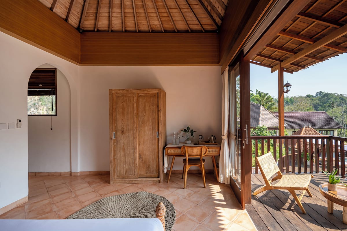A wooden balcony with a dining table, chairs, and a potted plant.