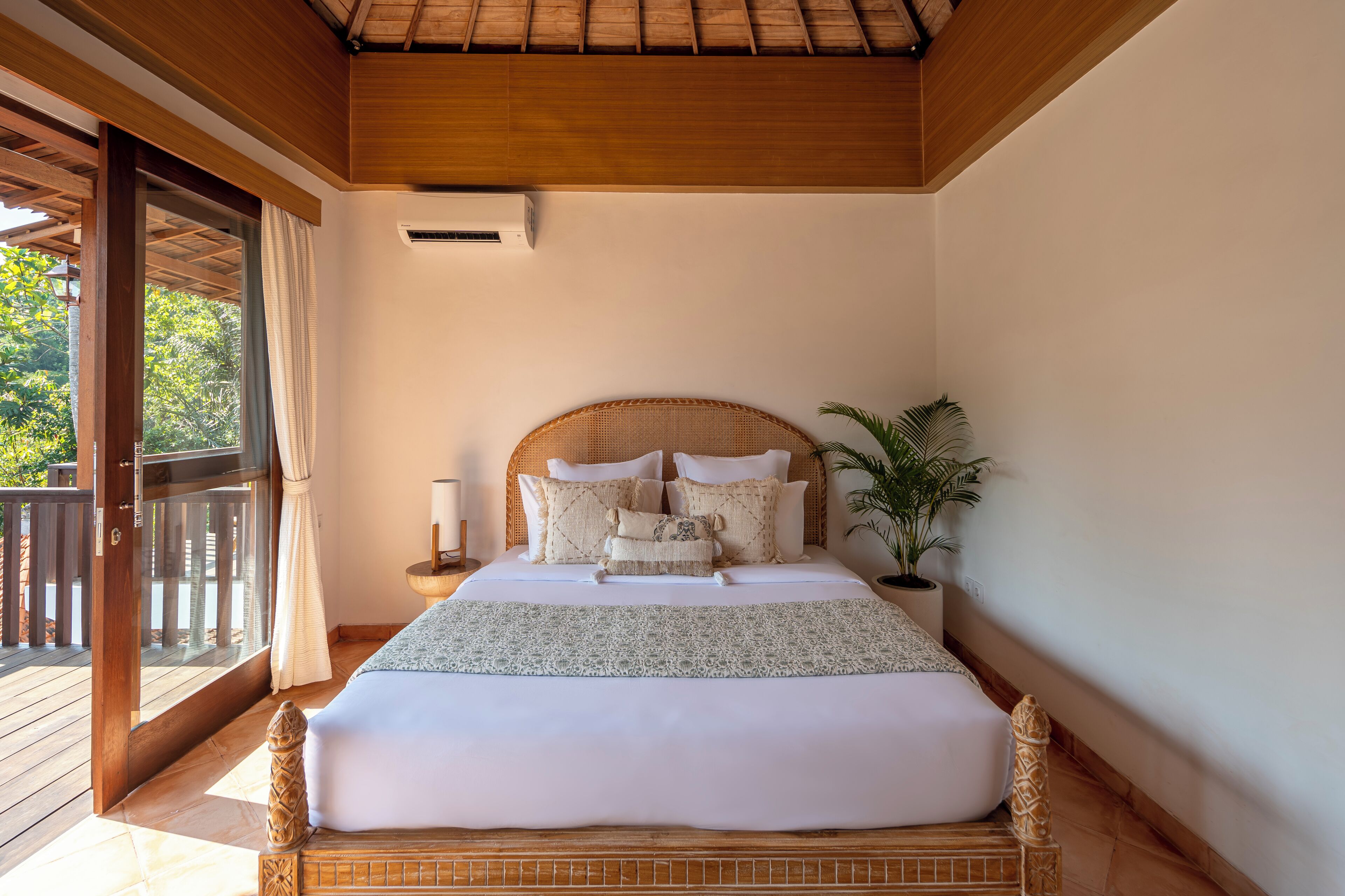 Un dormitorio espacioso con una cama grande, techo de madera y vistas al exterior.