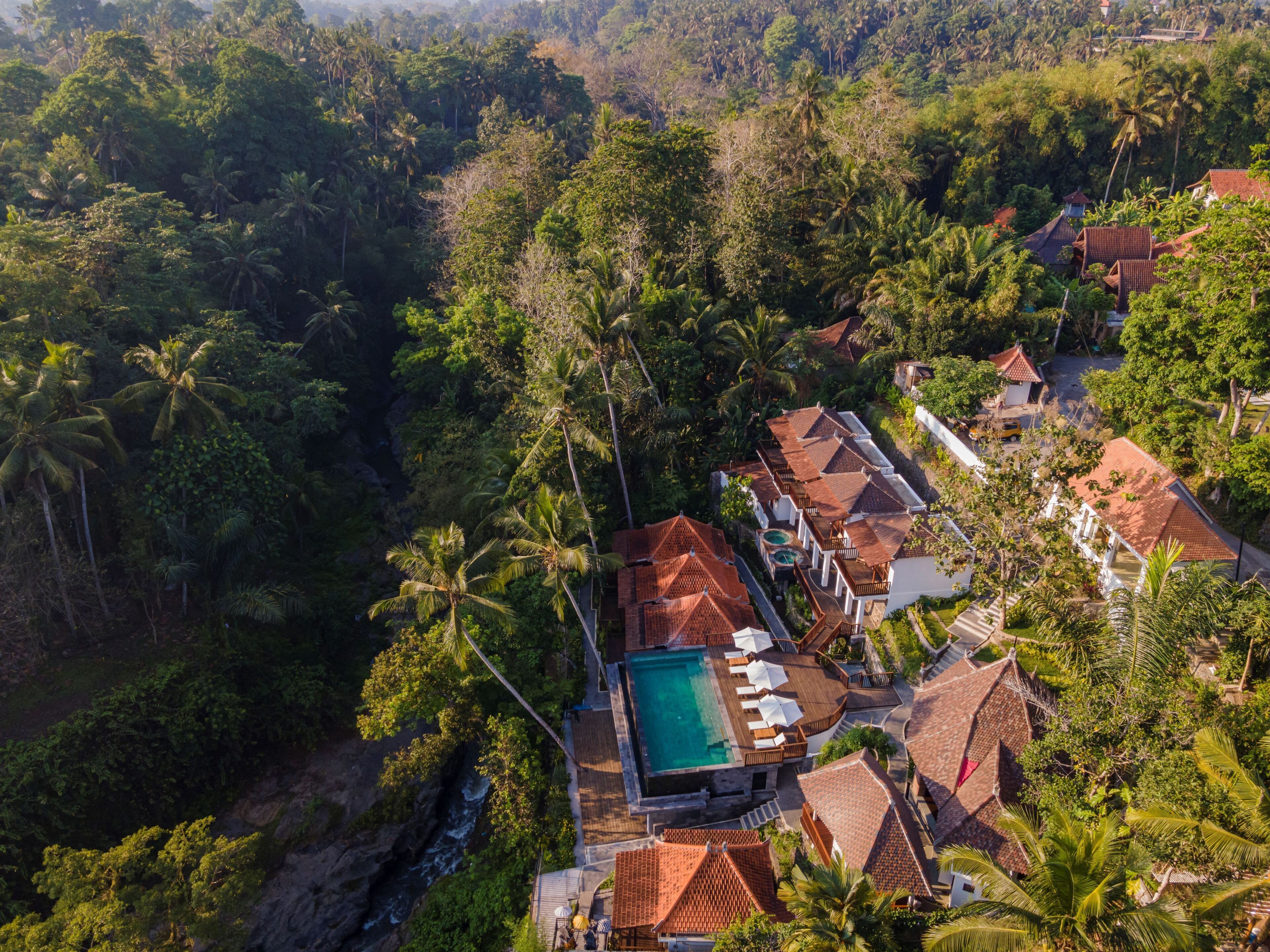 Vista aérea de un resort con varias villas, una piscina y exuberantes alrededores tropicales.
