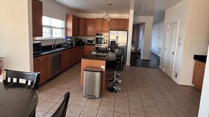 A modern kitchen with wooden cabinets, stainless steel appliances, and a central island with bar stools. - SPACIOUS Single Home near DC & National Harbor (Fort Washington)