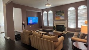A living room with a large flat-screen TV, a fireplace, and a sofa. - SPACIOUS Single Home near DC & National Harbor (Fort Washington)