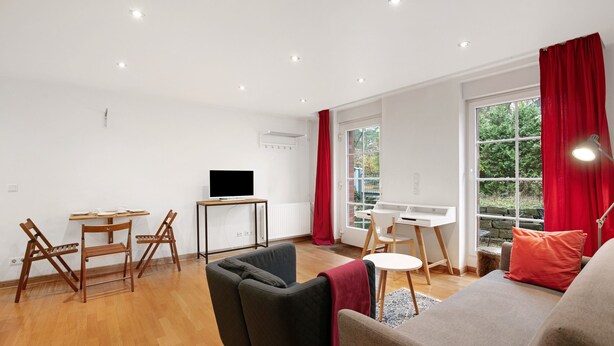 A modern living room with a sofa, chairs, a TV, and a dining area. - Apartment 'Grüne Oase In Der Großstadt' with Private Terrace, Garden and Wi-Fi (Berlin)