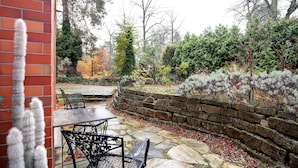 An outdoor patio with stone flooring, a brick wall, and a stone retaining wall. - Apartment 'Grüne Oase In Der Großstadt' with Private Terrace, Garden and Wi-Fi (Berlin)