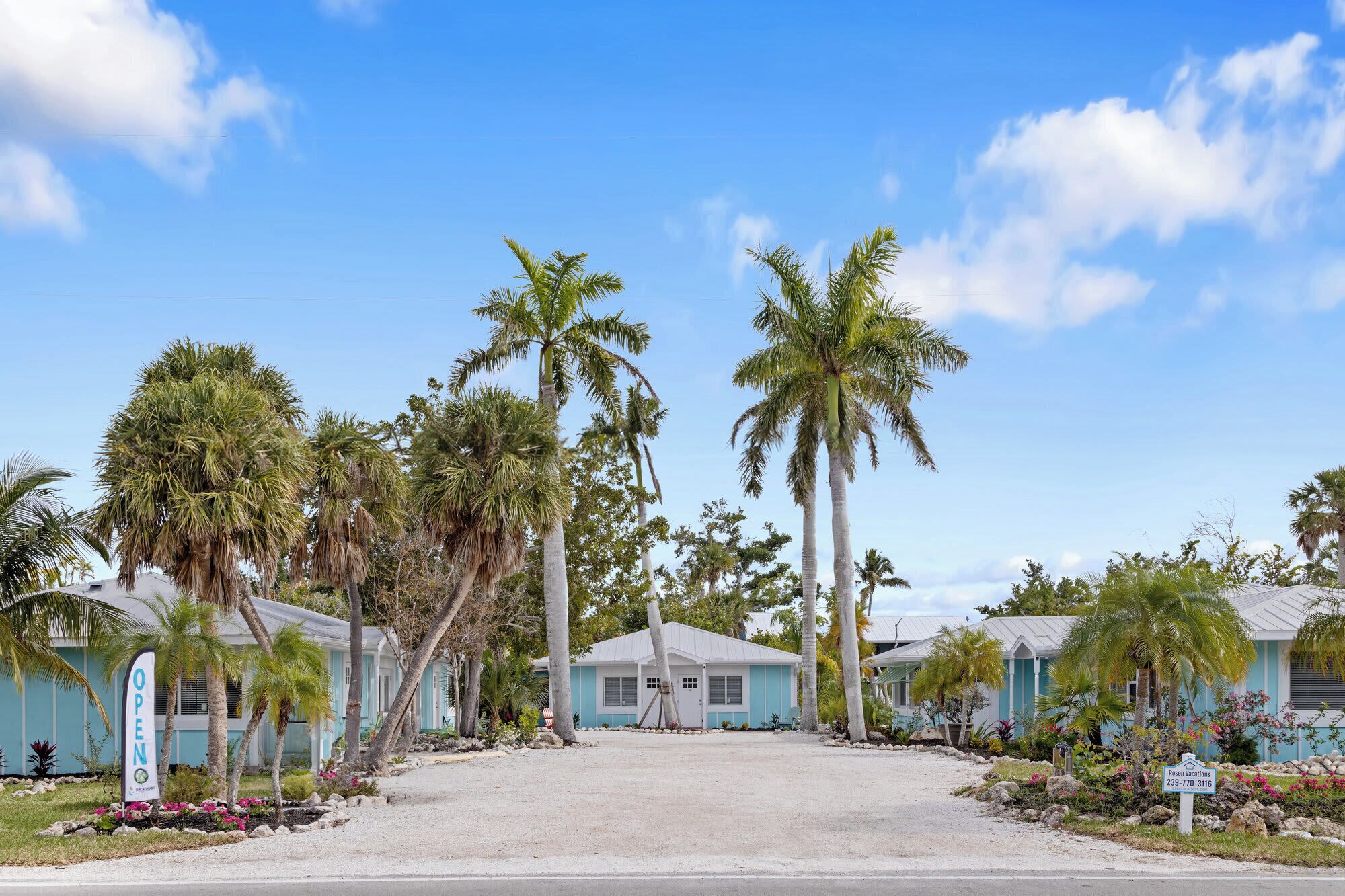 A coastal property with multiple buildings, palm trees, and a clear sky.