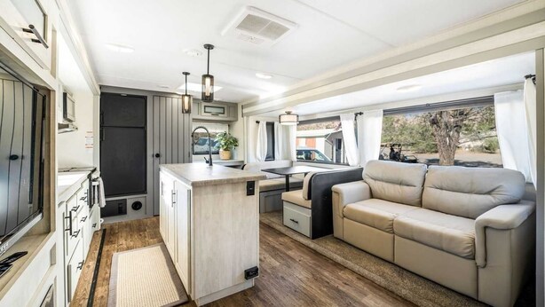 A compact RV interior with a kitchenette, a dining area, and a seating area with a sofa. - Desert Tiny Home B25: Relaxing Desert Accommodation w/ Comfort Amenities (Jacumba Hot Springs)