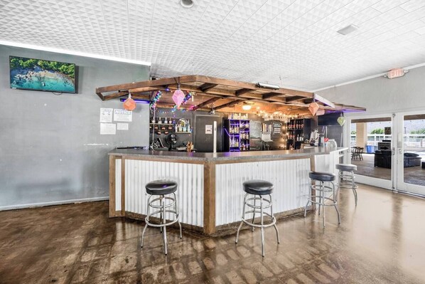 A bar area with a wooden ceiling, a TV on the wall, and a view of the outside.