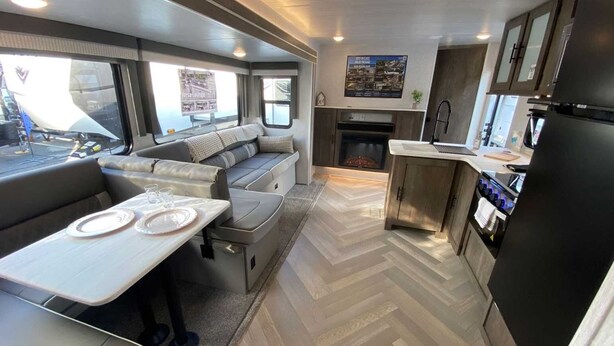 Interni di un camper compatto con angolo cottura, zona giorno con tavolo e camino.