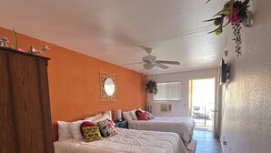 Ein Schlafzimmer mit zwei Betten, einem Deckenventilator und Blick ins Freie.