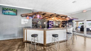 Eine Bar mit Holzbalkendecke, einem Fernseher an der Wand und Blick ins Freie.