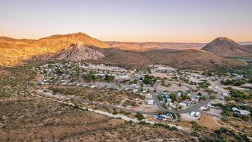 An aerial view of a desert town with winding roads and sparse vegetation, surrounded by mountains.