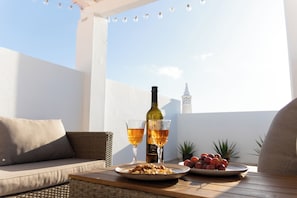 A balcony with a wicker sofa, a table with a bottle of wine, glasses, and plates of food. - Großes Haus mit Sonniger Dachterrasse - 3 Schlafzimmer - 6 Personen - Top Lage (Vila do Bispo)