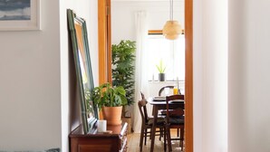 Ein Flur mit Essbereich, einem auf einem Ständer platzierten Bild und einem Blumentopf.