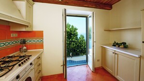 A kitchen with a gas stove, cabinets, and a view of a balcony. - Ancient mansion with breathtaking views amid ancient olive and citrus trees (Praiano)