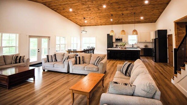 Un salón espacioso con techo de madera, zona de cocina y comedor.