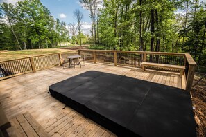 Een houten terras met een zwarte mat, een bank en een tafel.