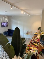 Una habitación moderna con una larga mesa buffet repleta de diversos alimentos, un sofá azul, una araña y un televisor de pantalla plana en la pared.