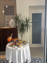 Una mesa con comida y bebidas, un muro con diseño y una puerta que indica “SPA & WELLNESS”.