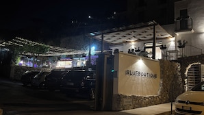 Un edificio con un letrero que dice "BLUEBOUTIQUE" en la entrada, una pared de piedra y coches aparcados.