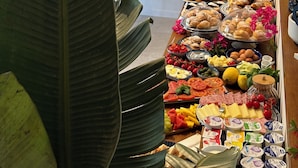 Una mesa de buffet con diferentes platillos y una planta al frente.